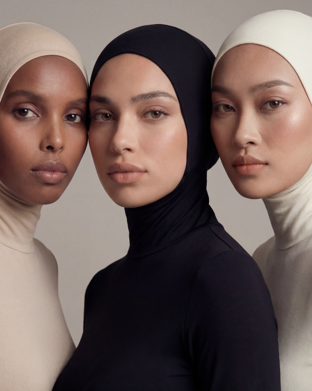 Three women wearing The Hijab Bodysuit in Buttermilk, Onyx and Ivory